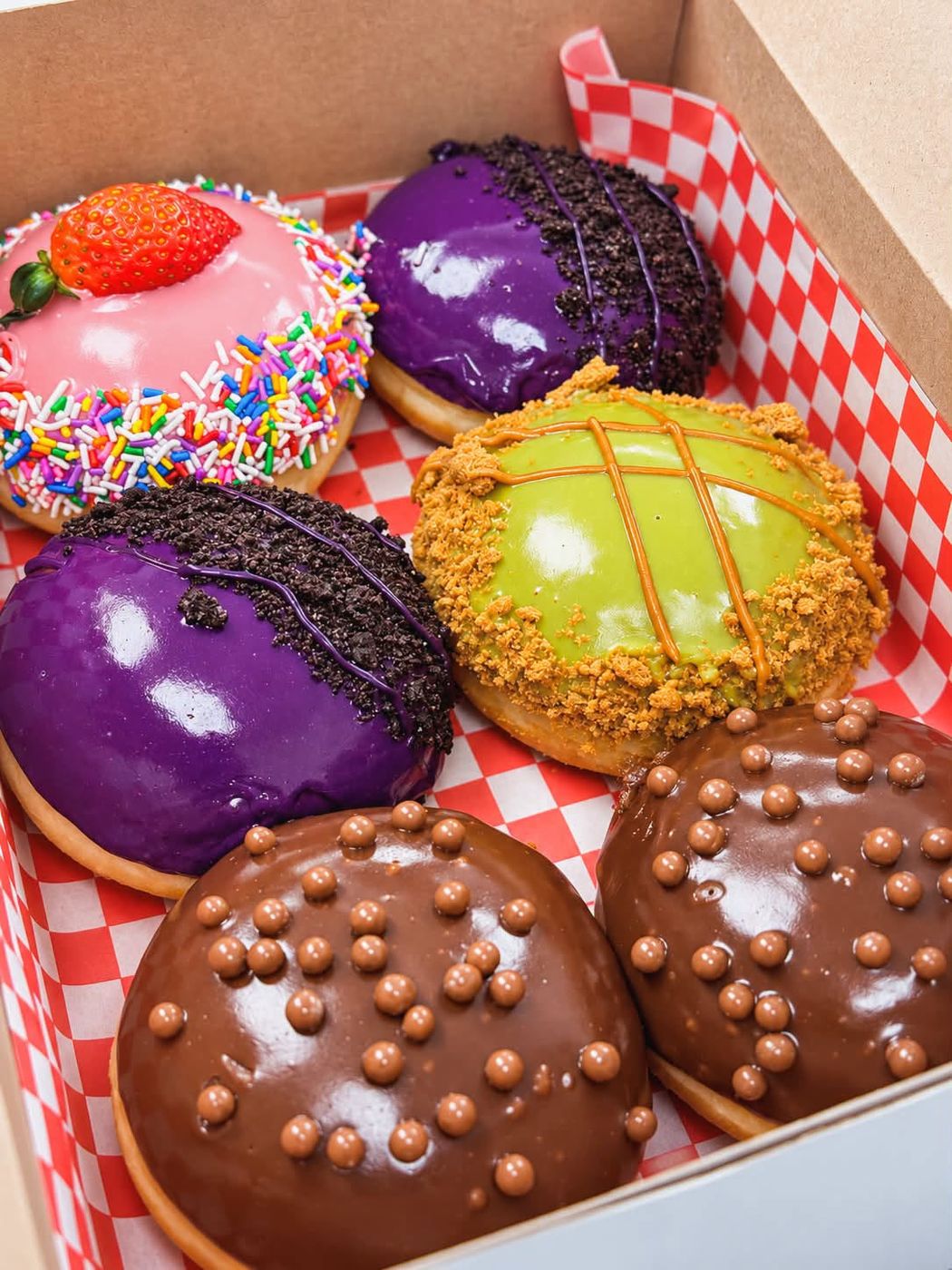 Ube, matcha, strawberry and Belgian chocolate glazed donuts in a gingham-lined box