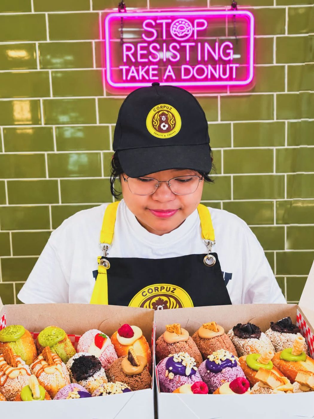 Two boxes of donuts under the pink neon sign